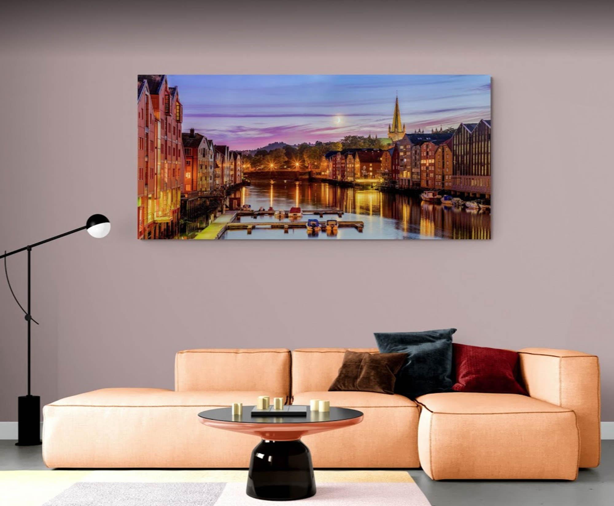 Moderne stue med en stor sofa, et rundt bord og et maleri av en vakker havneutsikt.