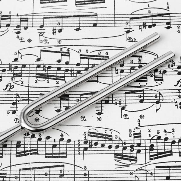 En stemmesnor ligger på et ark med noter, som viser musikknotasjon og rytmer.
