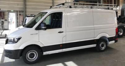 Hvit varebil med takstativ, parkert i en lagerbygning med betonggulv.
