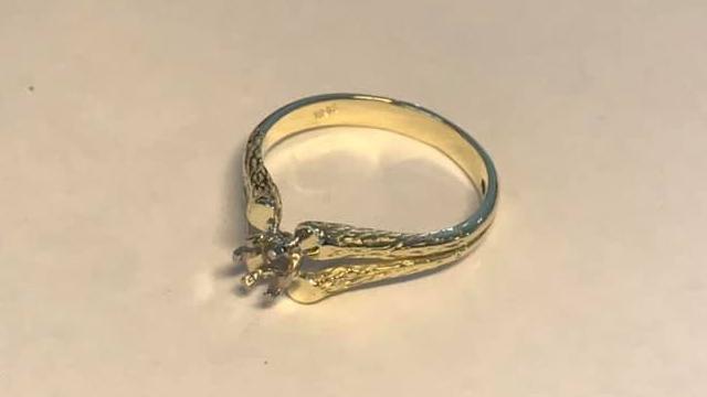 En elegant gullring med tre diamanter og intrikate detaljer på sidene.