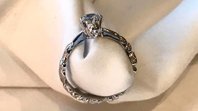 En elegant forlovelsesring med en stor diamant og intrikate detaljer på ringens band.