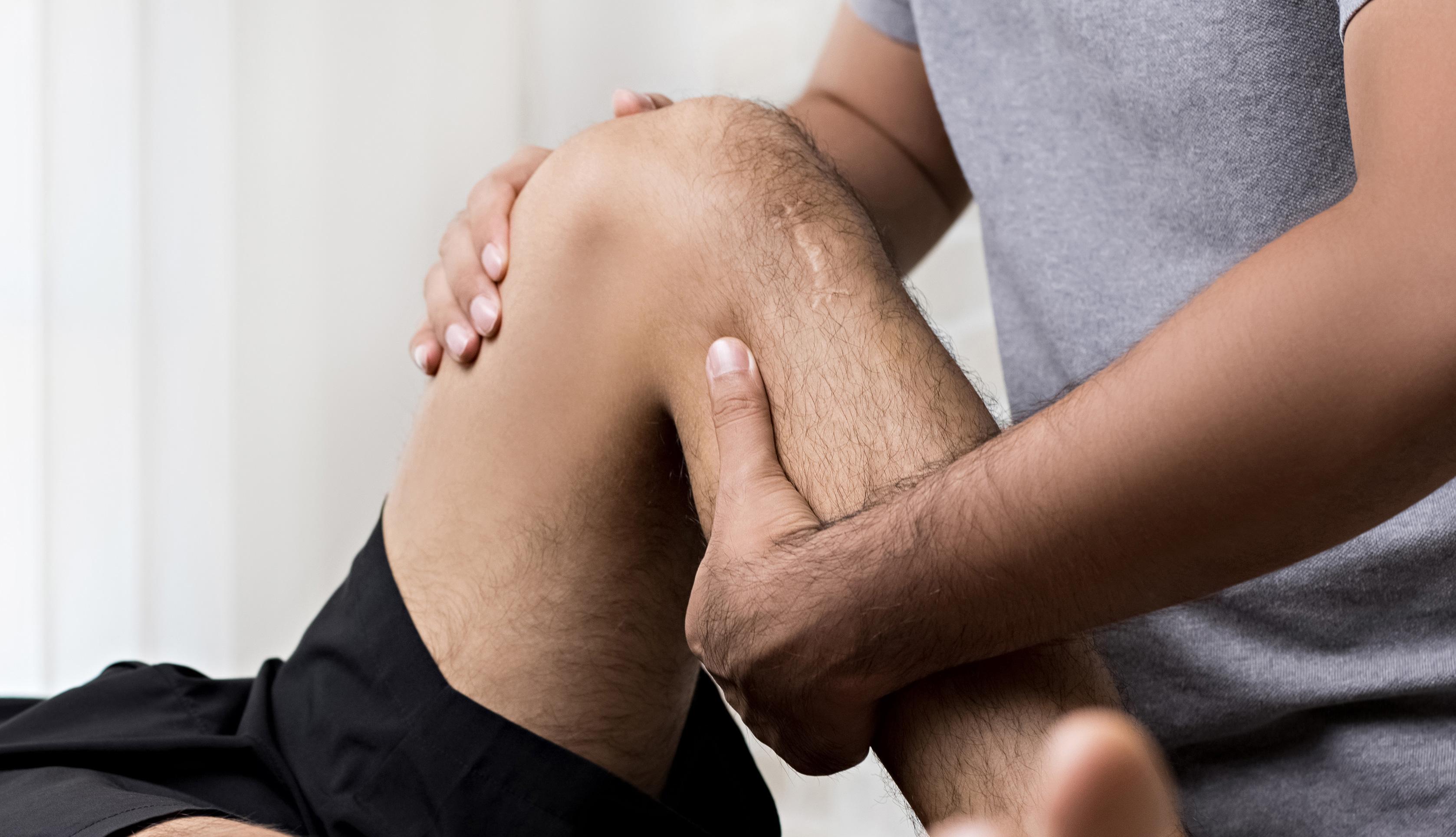 En fysioterapeut utfører knebehandling på en pasient med fokus på rehabilitering av skader.