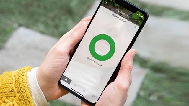 En person holder en smarttelefon med en grønn sirkel på skjermen, som viser en app for valg.