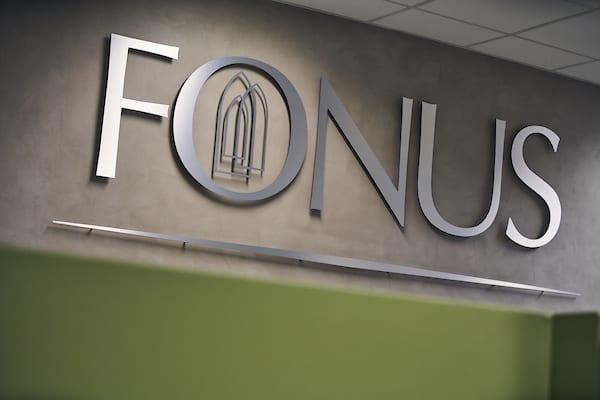 FONUS-logoen på en vegg i et moderne kontorlandskap med nøytral bakgrunn.