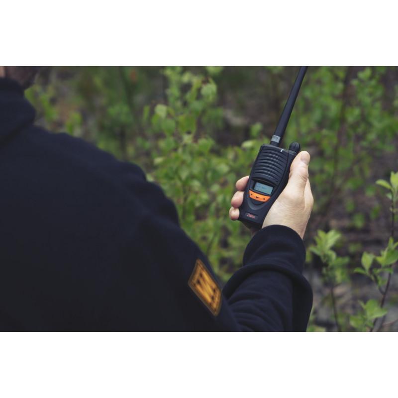 En person holder en håndholdt radio i en grønn skog.