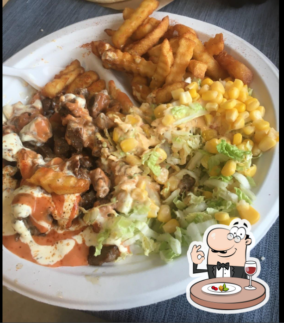 En tallerken med pommes frites, kjøtt, salat, mais og saus, servert i en restaurant.