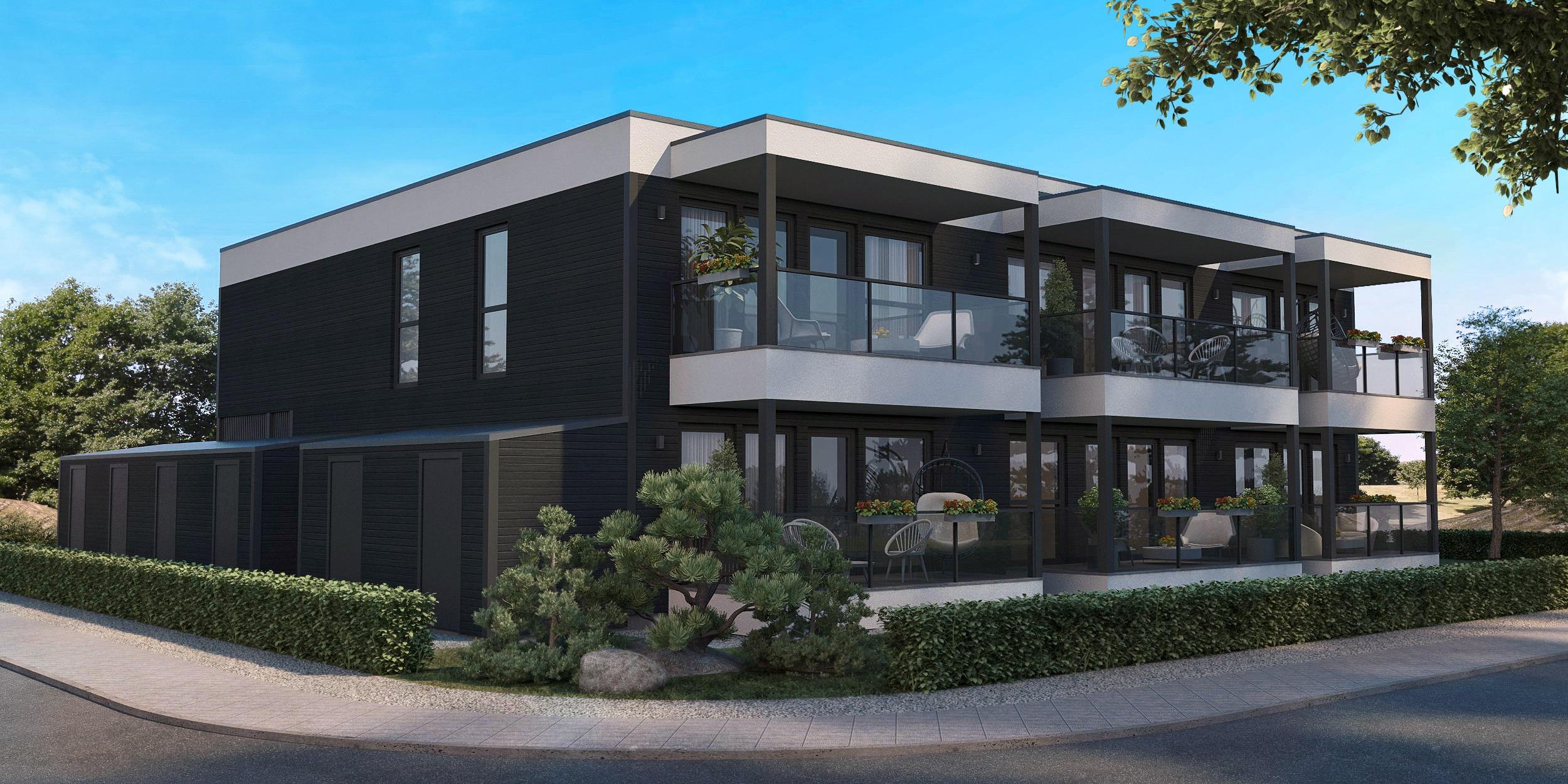 Moderne leilighetsbygg med balkonger, grøntområde og asfaltert vei i forgrunnen.