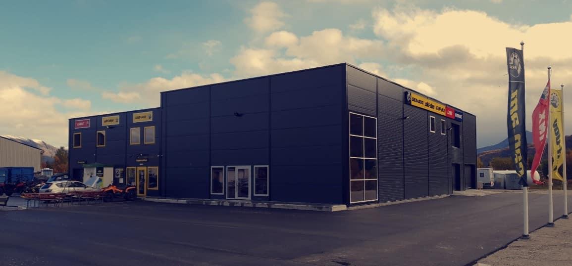 Moderne bygning med store vinduer og skilt, beliggende på en asfaltert vei.