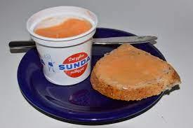 En tallerken med brødskive med smør og en kopp med appelsinjuice.
