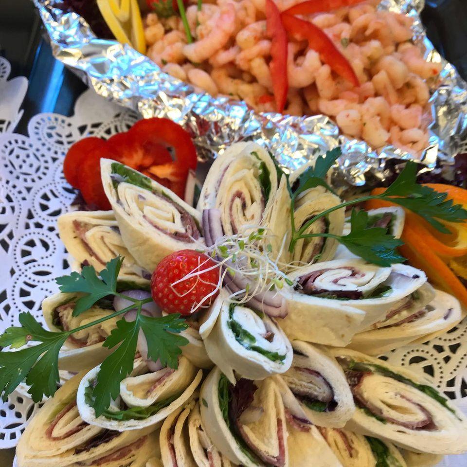 Fargerik tallerken med rullekebab, reker og grønnsaker, dekorert med urter og bær.