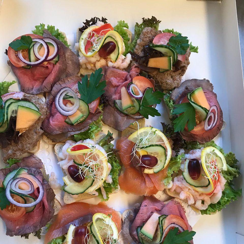 Et fat med småretter bestående av kjøtt, reker, grønnsaker og urter, dekorert med salatblader.