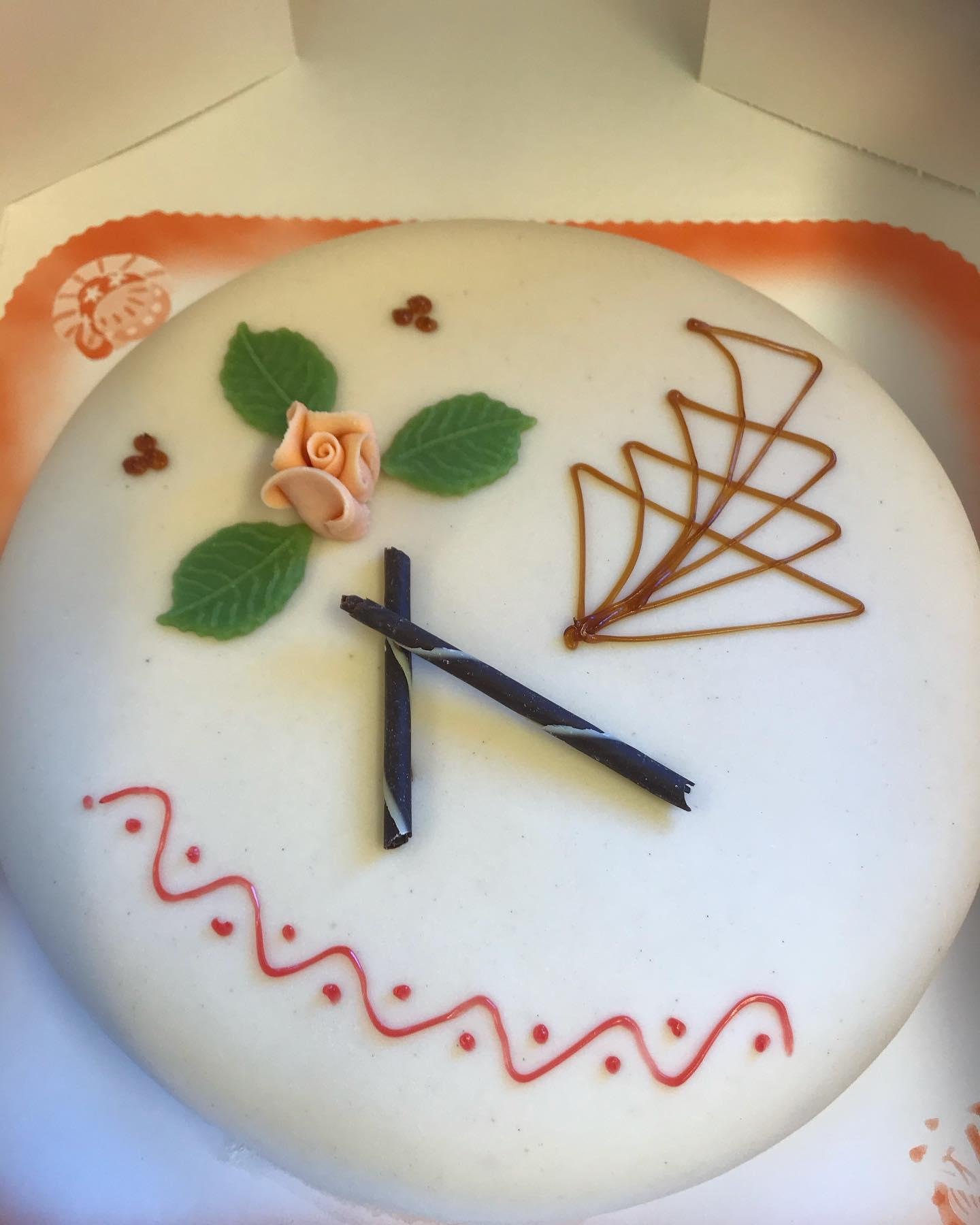 Kake dekorert med roser, blader og klokke, med detaljer i marsipan og sjokolade.