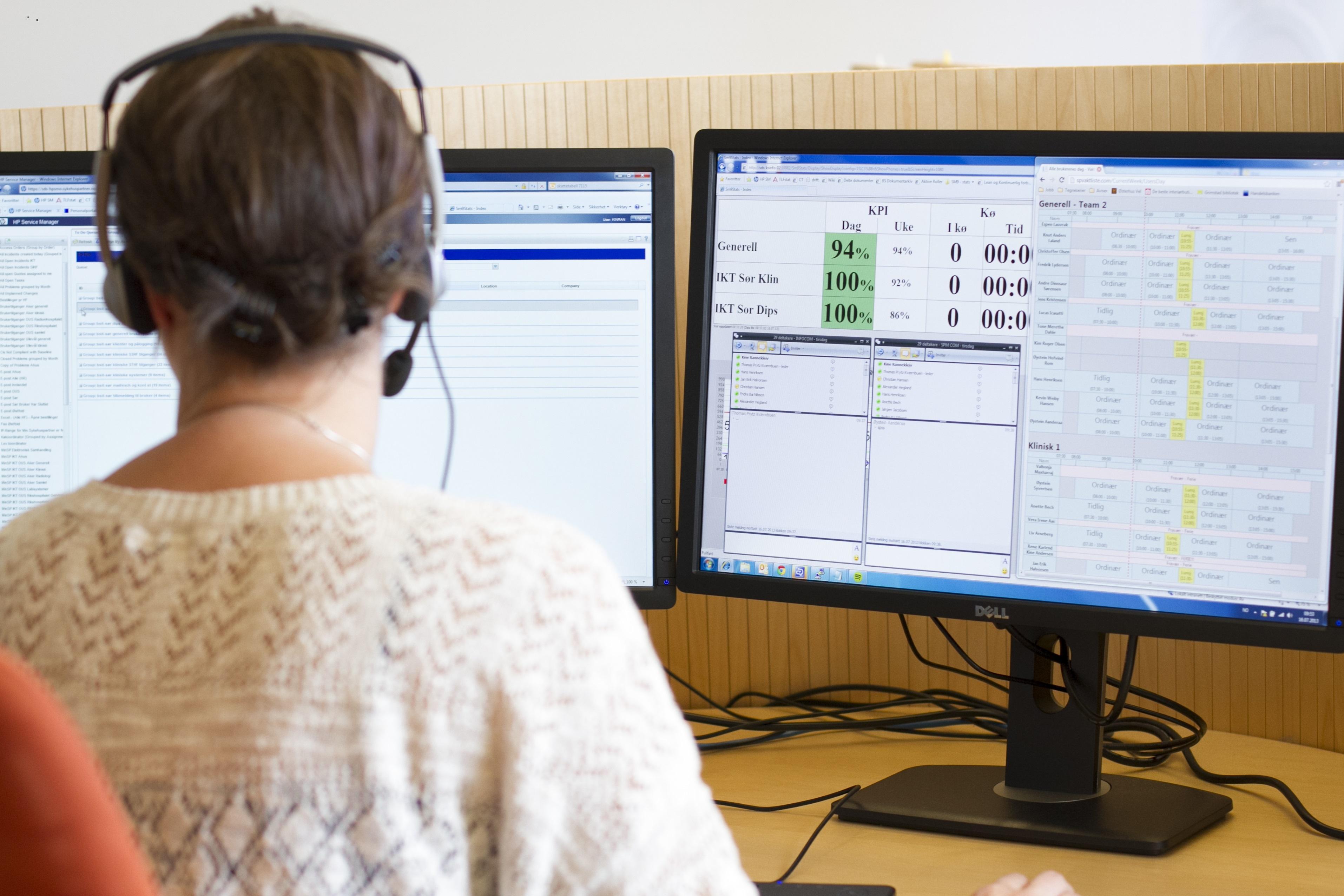 En person med headset sitter foran to dataskjermer som viser ulike programmer og data.
