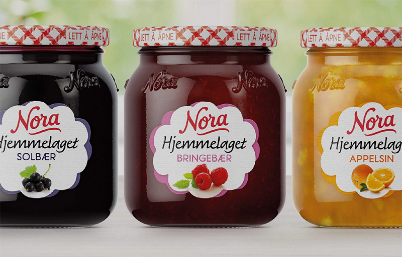 Tre glass med syltetøy fra Nora: solbær, bringebær og appelsin, med karakteristiske etiketter og røde lokk.
