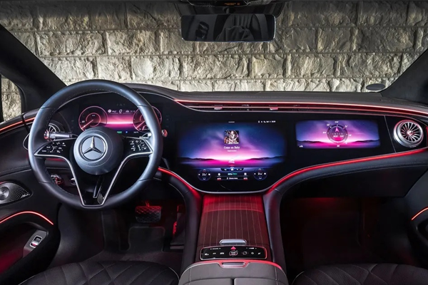 Interiør av en Mercedes-Benz med moderne skjerm, rødt lys og luksuriøse detaljer.