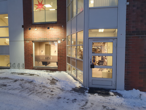 En butikkfasade med store vinduer, snø på bakken og en rød stjerne hengende over inngangsdøren.