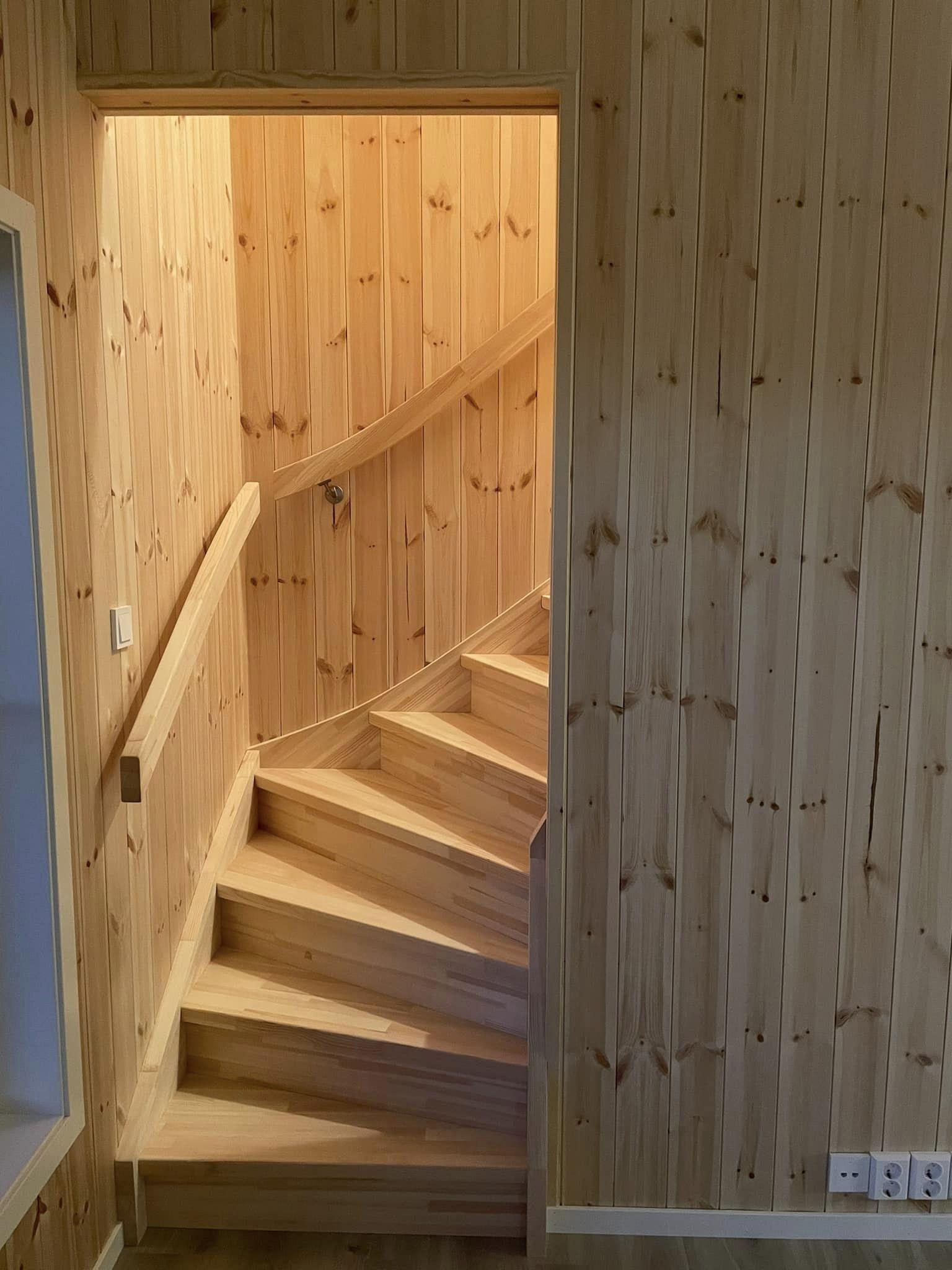 Trappen i en trevegg med lys som skinner nedover, gir en koselig atmosfære i rommet.