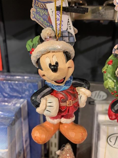 Mickey Mouse-figur i julekostyme med grønn krans og rød jakke, stående på en svart base.
