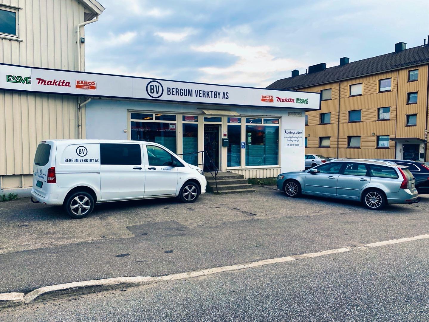 Butikken Belgen Værkty AS med hvit varebil og grå bil parkert foran bygningen.