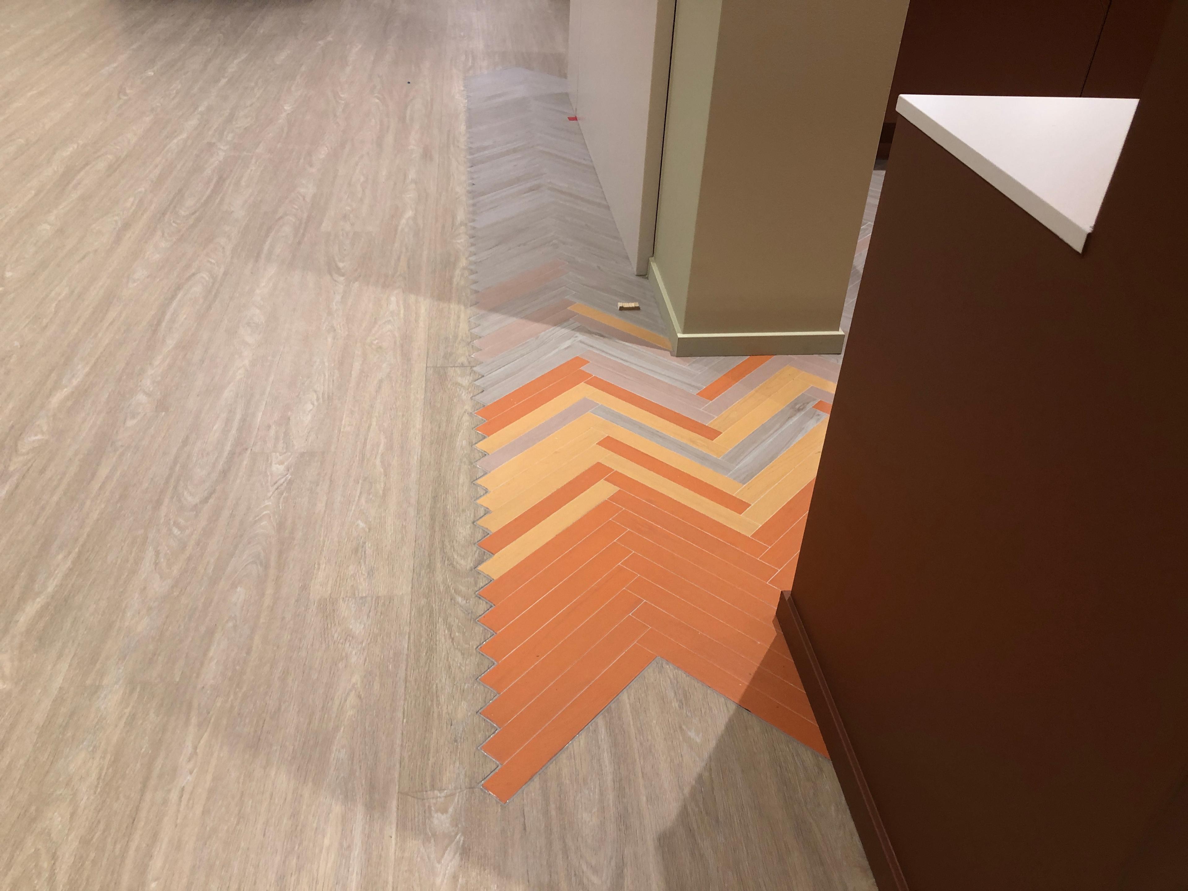 Gulv med mønster i oransje og grått, som danner en zigzag-form, i en moderne innendørs setting.