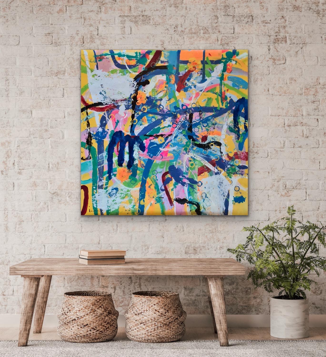 Fargerik abstrakt kunst på veggen over et trebord med kurver og en plante i stuen.