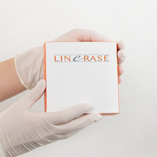 Hånd som holder en eske med produktet LineErase, iført engangshansker, mot en hvit bakgrunn.