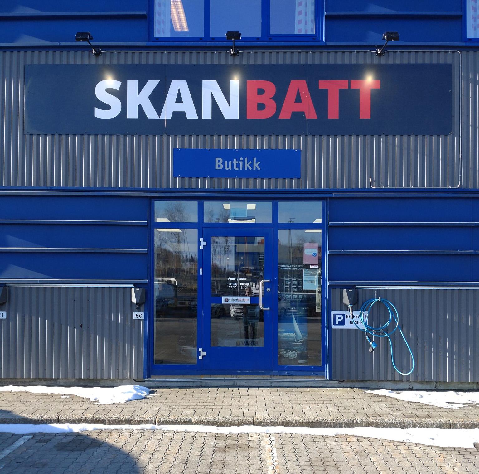 Inngang til Skanbatt butikk med blå fasade og skilt over døren. Snø på bakken foran.
