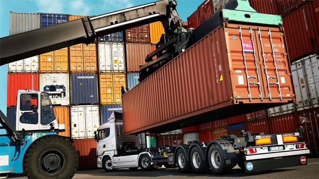 Lastebil som laster en container med en kran i en havn fylt med fraktcontainere.