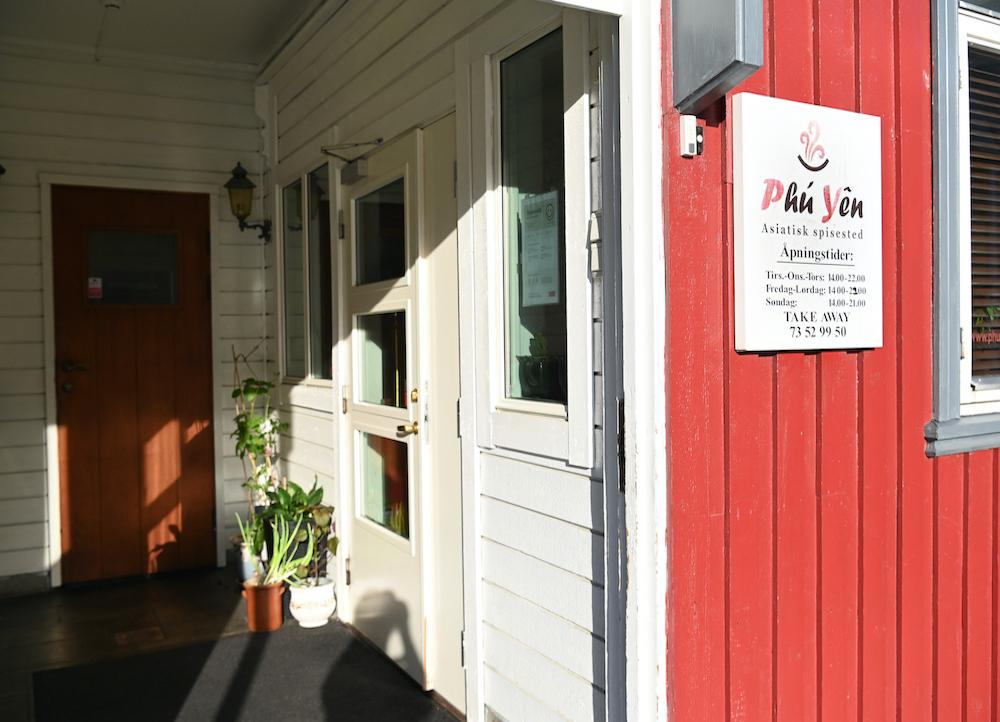 Inngangspartiet til en restaurant med rød vegg og skilt som viser navnet "Pål Jøn".