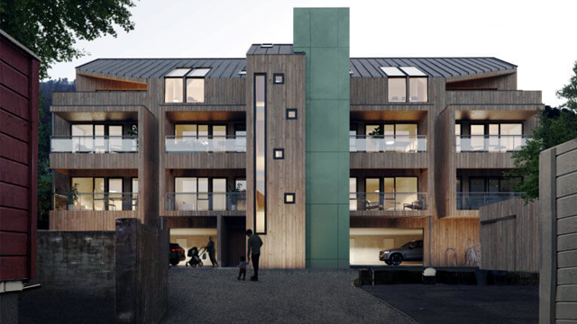 Moderne leilighetsbygg med treverk og grønn fasade, omgitt av parkering og trær.