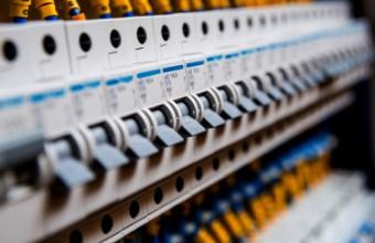 Nærbilde av en elektrisk tavle med flere brytere og sikringer i forskjellige farger.