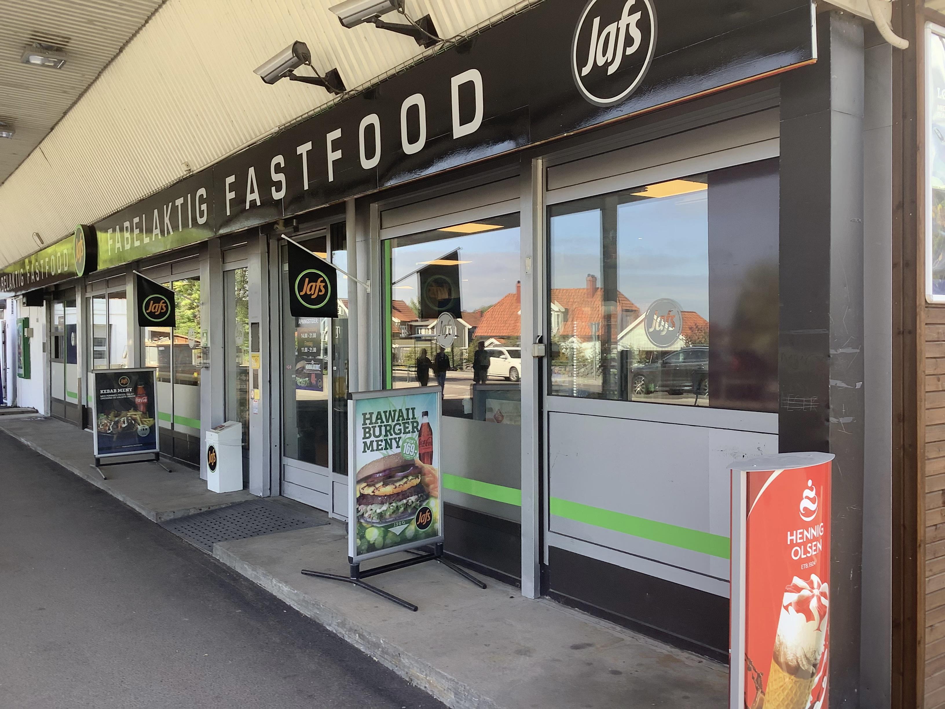 Fastfoodrestaurant med store vinduer og skilt som viser menyer og tilbud utenfor.