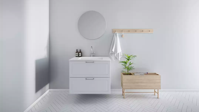 Moderne baderom med hvit servant, speil, håndkleholder og en plante i en trebeholder.