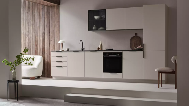 Moderne kjøkken med grå skap, svart benkeplate og stilige detaljer i et lyst rom.