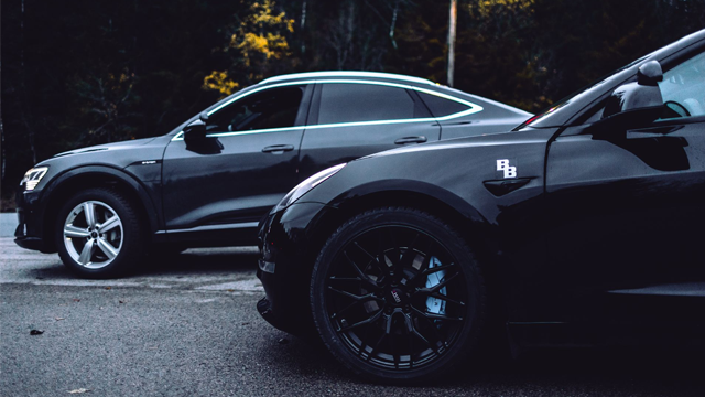 To svarte SUV-er parkert på en grusvei, med moderne design og stilige felger.