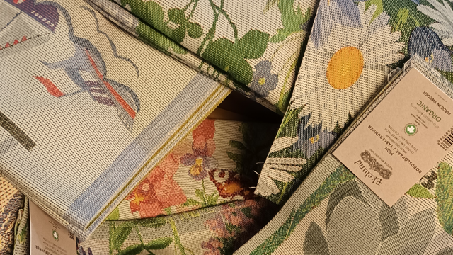 Fargerike tekstiler med blomster- og mønsterdesign, stablet sammen i en haug.