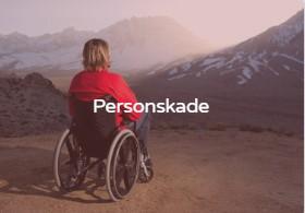 En person i rullestol ser ut over fjellandskapet ved solnedgang.