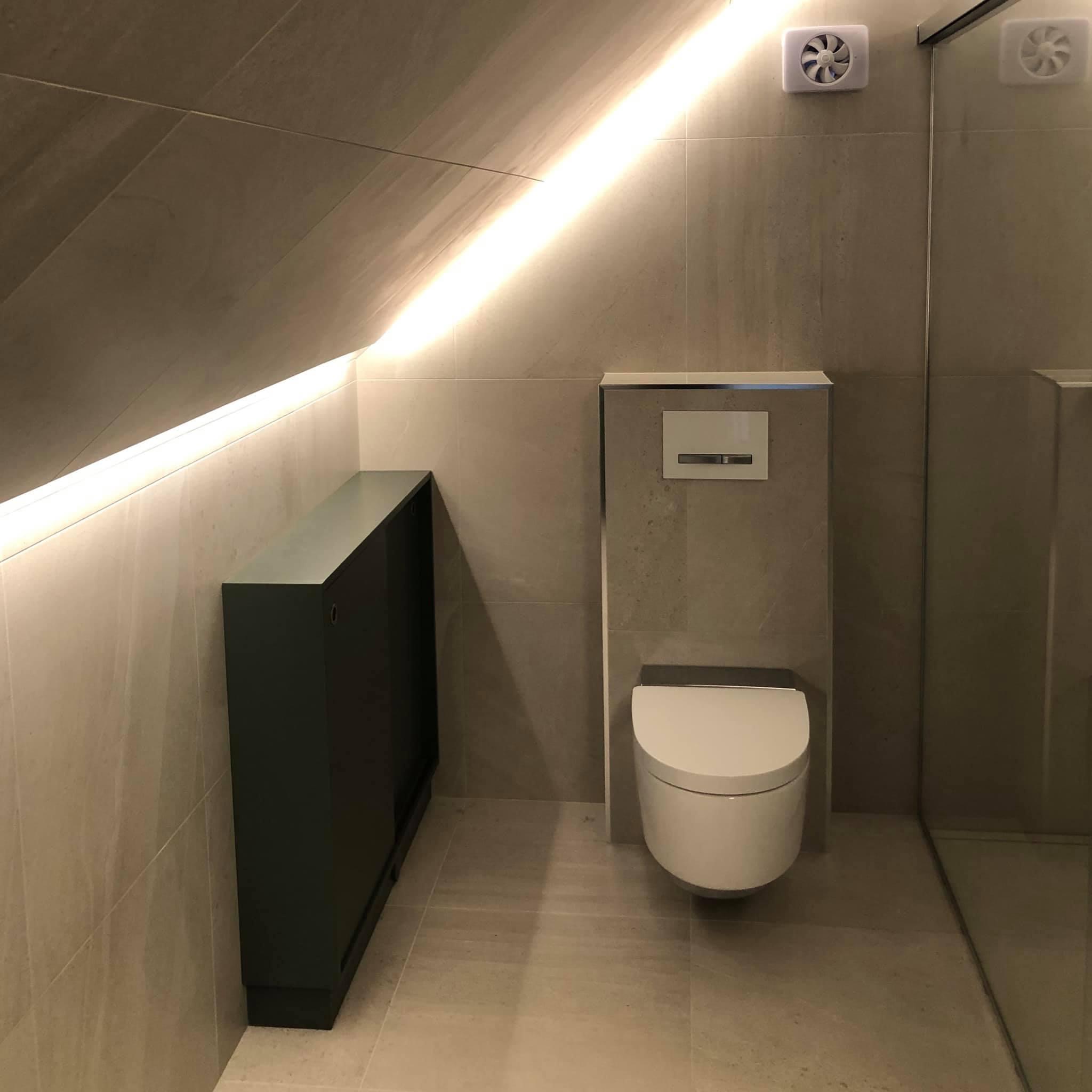 Moderne bad med skråtak, toalett og dusj, belyst med LED-lys og stilige fliser.