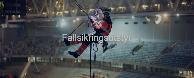 En person i fallskjermutstyr som klatrer ned fra taket i en stor arena.