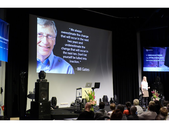 En presentasjon med Bill Gates på skjermen, som snakker om fremtidige endringer, med publikum i salen.