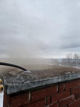 Utsikt fra en mursteinsvegg med tåke og grå himmel i bakgrunnen.