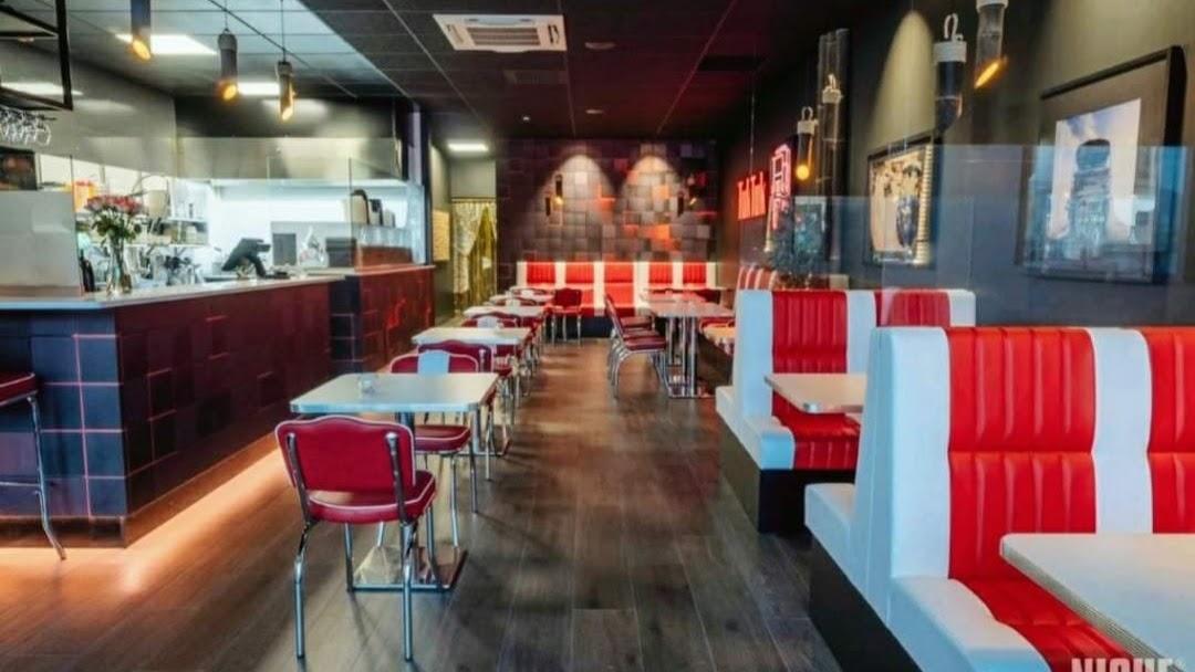 Moderne restaurantinteriør med røde og hvite sitteplasser, barområde og stilige veggdekorasjoner.