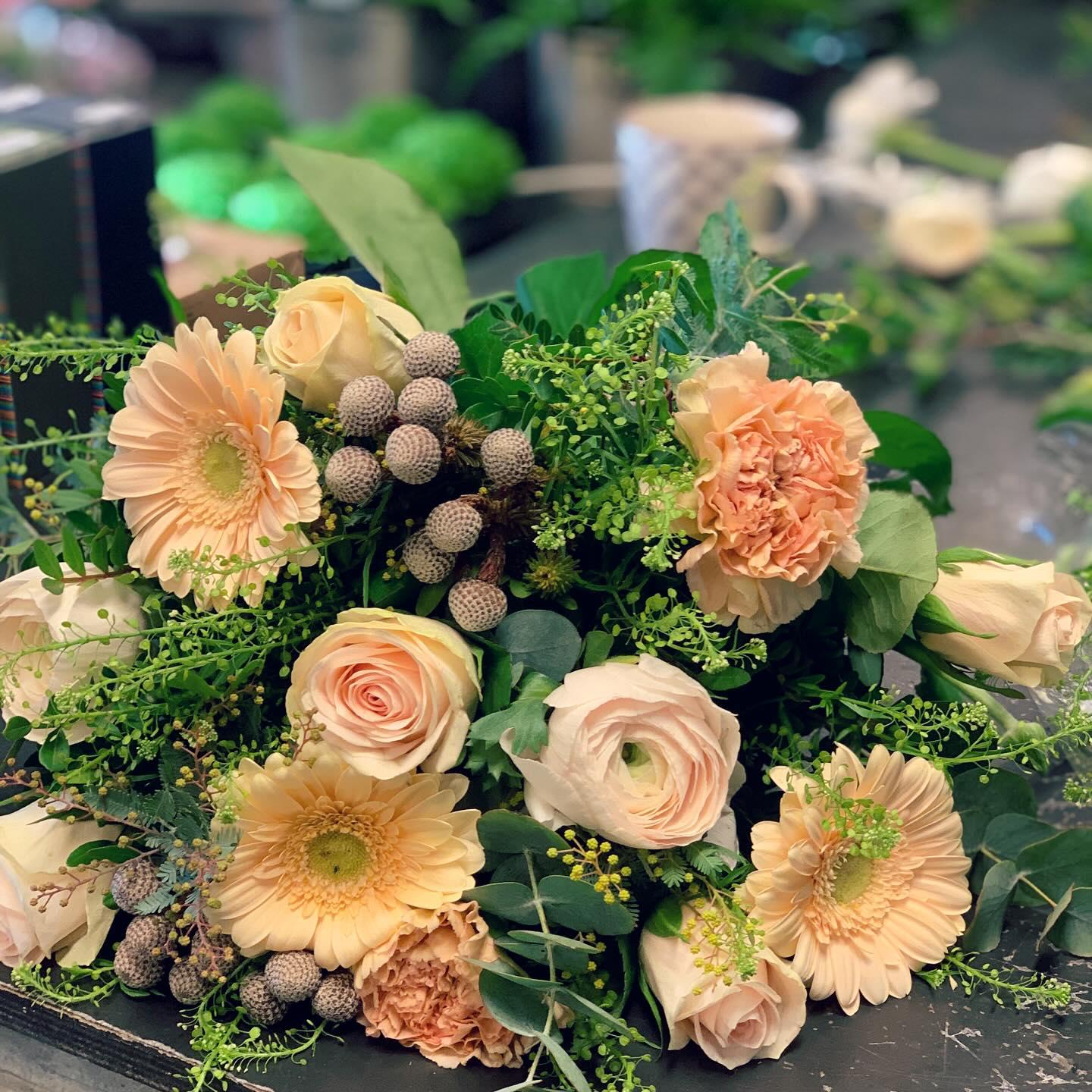 En vakker bukett med ferske blomster, inkludert roser, gerbera og grønt, dekorert med bær og blader.