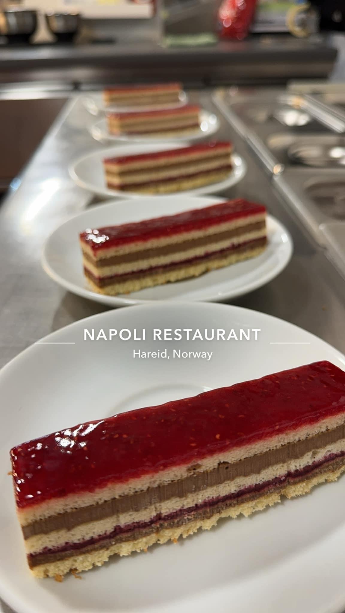 Lag med kake på tallerkener, med lag av krem, bær og gelé, servert på Napoli Restaurant i Norge.