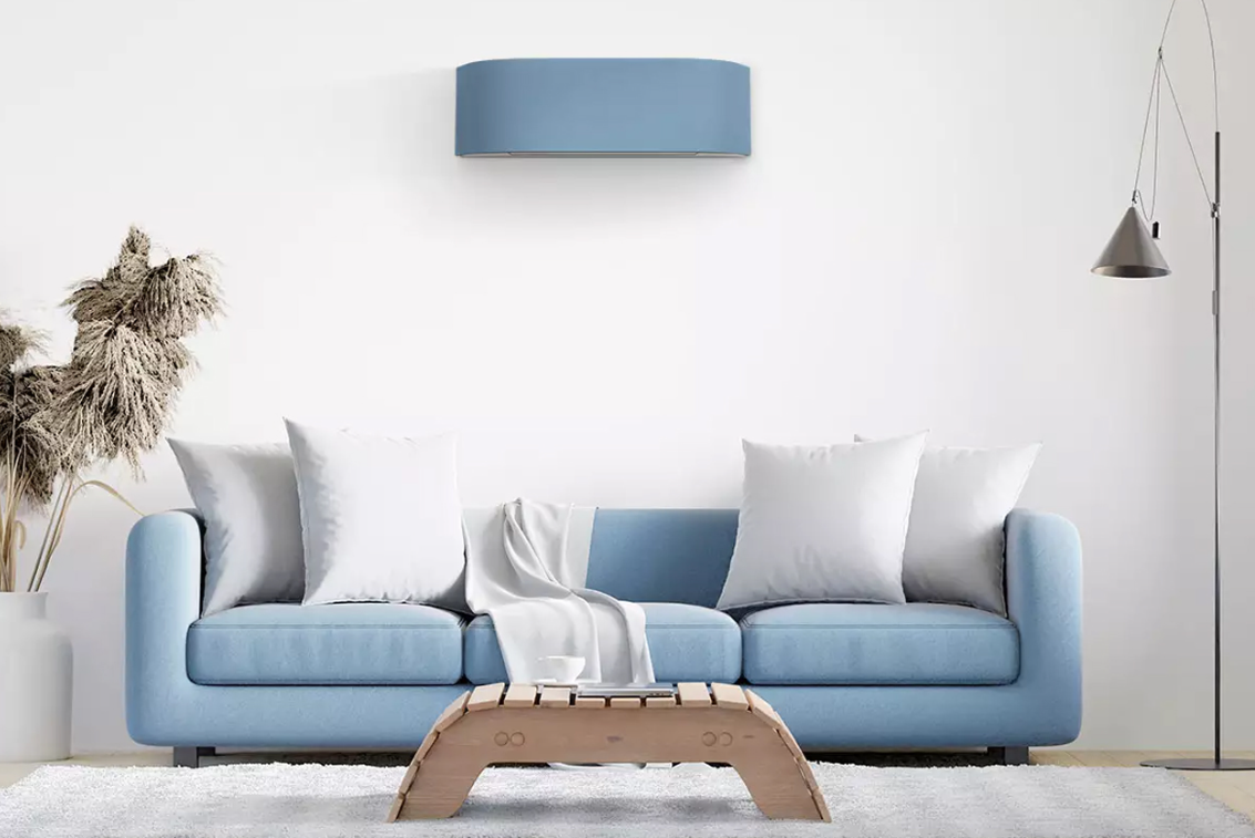 Blå sofa med puter, et lyst rom med en moderne lampe og en dekorativ hylle på veggen.