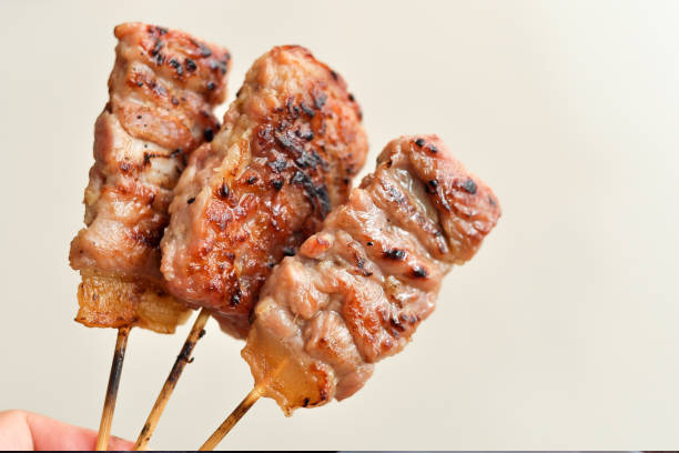 Tre grillspyd med saftig kjøtt, perfekt stekt og gyllenbrunt, holdt av en hånd.
