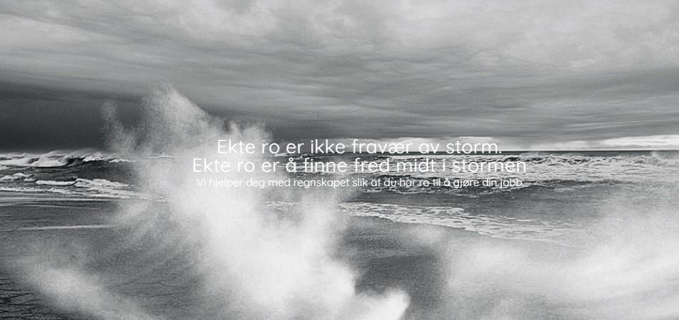 Bølgesprut mot stranden under en dramatisk, grå himmel med mørke skyer.