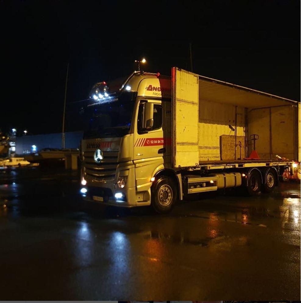 En lastebil parkert om natten med lys som reflekteres på den våte veien.