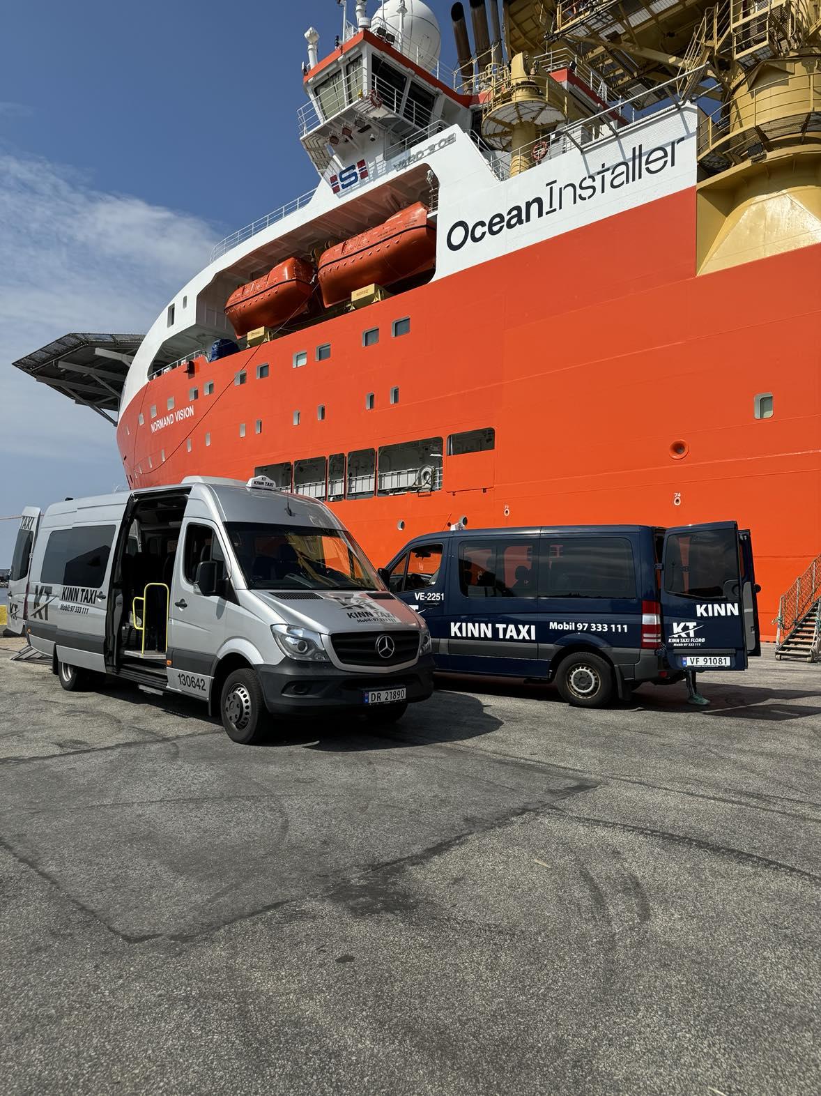 To storebiler parkert foran en stor offshore båt med navnet Ocean Installer.