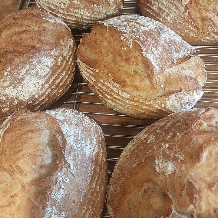 Nystekte brød med sprø skorpe på en bakerist, med melstøv på overflaten.
